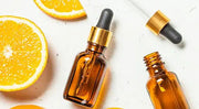 Vitamin C serum bottles and citrus fruits on white background – skincare guide 2025